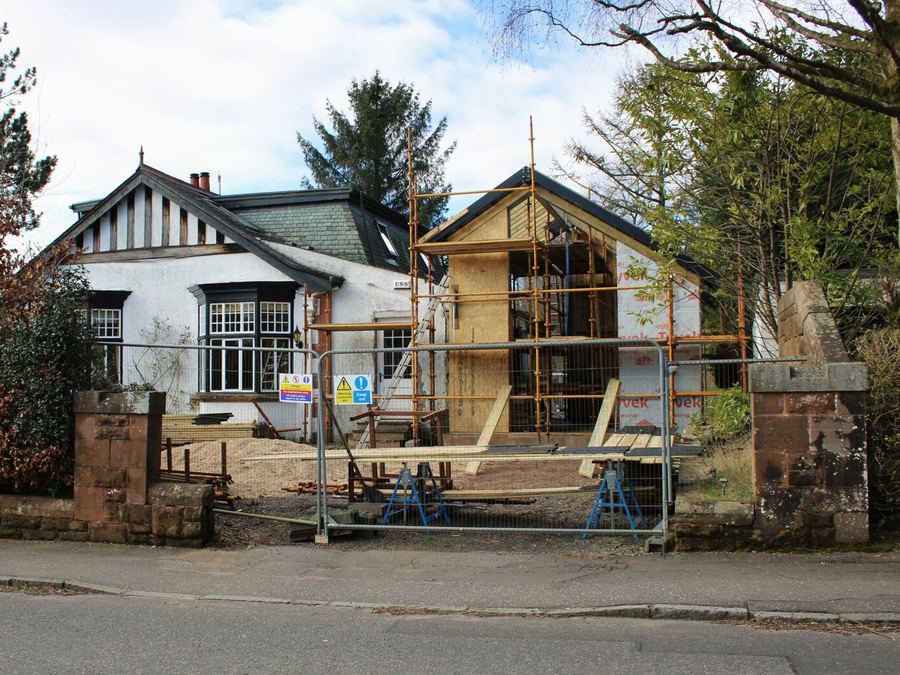 A timber-framed extension being built behind site fencing